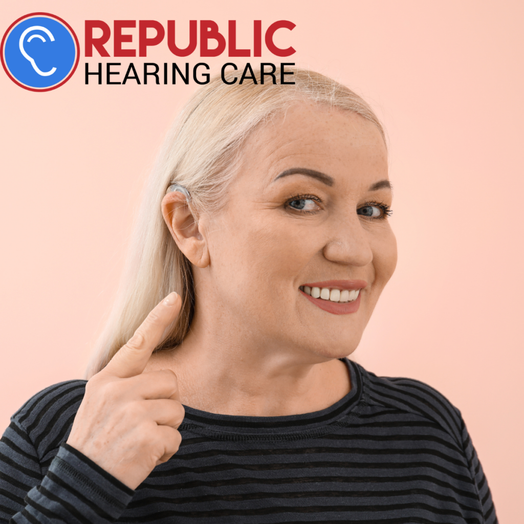 lady pointing at the hearing aid in her ear