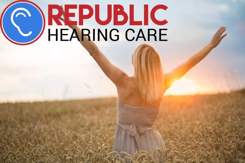 woman standing with her arms outstretched in a field at sunset